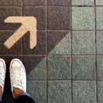 A pathway with an arrow guiding a pair of feet, illustrating the concept of a Gemba walk.